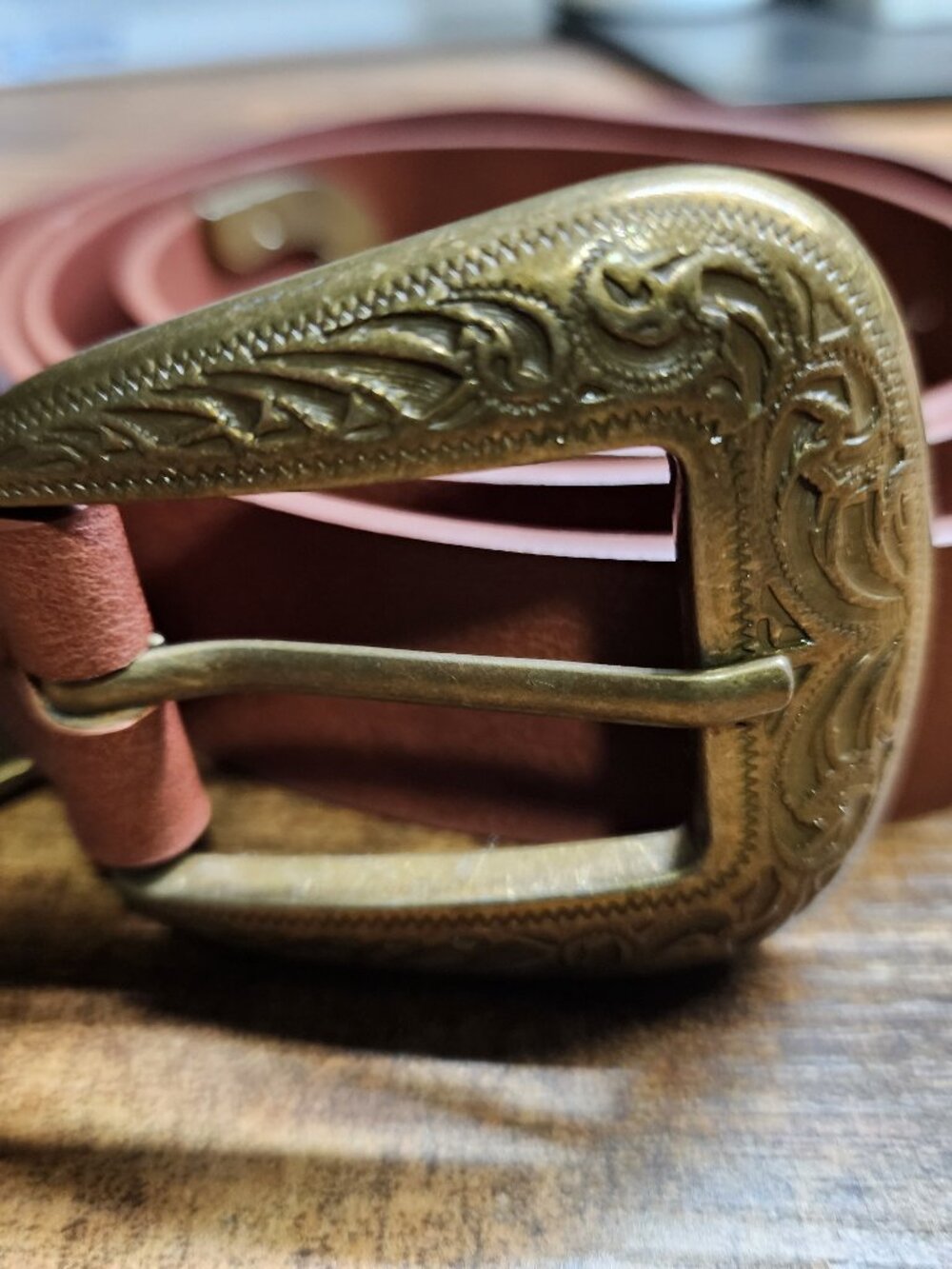 Tan leather western belt featuring an ornate, antique brass-engraved floral buck